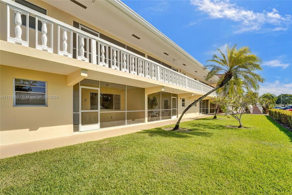 Front view of a two-story building with a white railing and screened porches.