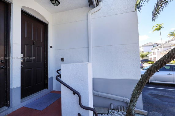Front view of a building entrance with a black door and a railing.