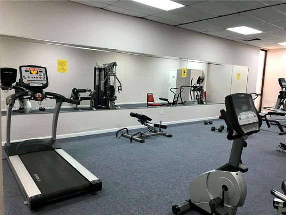 Indoor gym area with exercise equipment including treadmills and stationary bikes.