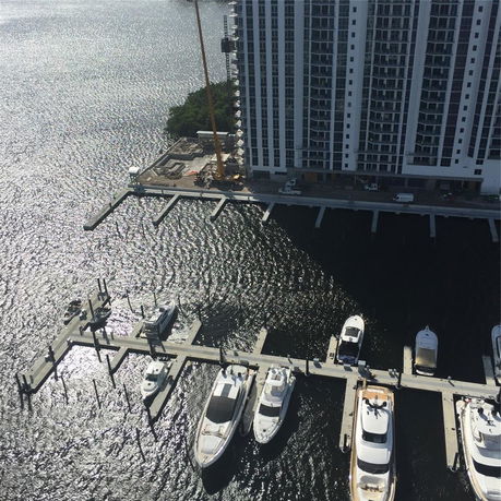 View of a high-rise building next to a marina with several boats docked.
