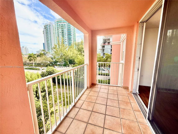 View from a balcony overlooking greenery and tall buildings.