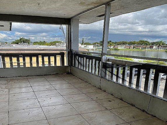 A tiled outdoor area with a railing, offering a view of buildings and trees in the distance.