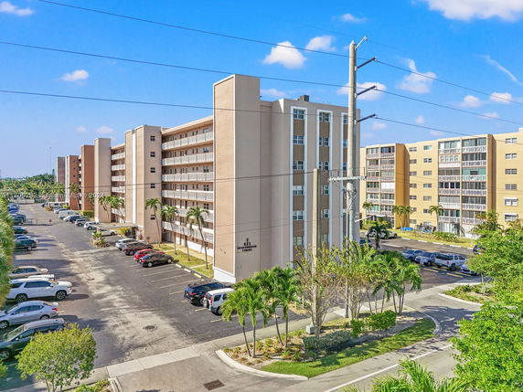 Front view of a multi-story apartment building with adjacent parking areas.