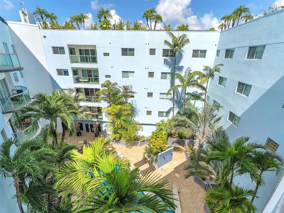 View of a multi-story apartment complex with palm trees in the courtyard.