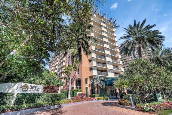 Front view of a multi-story building with balconies and a landscaped entrance.