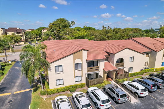 Front view of a two-story residential building with a tile roof and parking area.