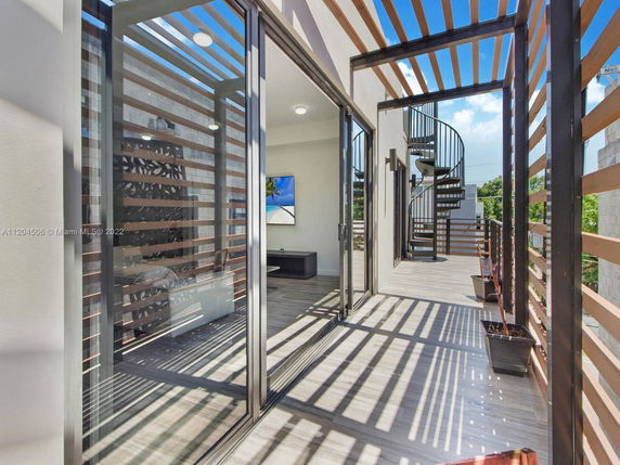Outdoor balcony area with spiral staircase and wooden slat privacy screen.