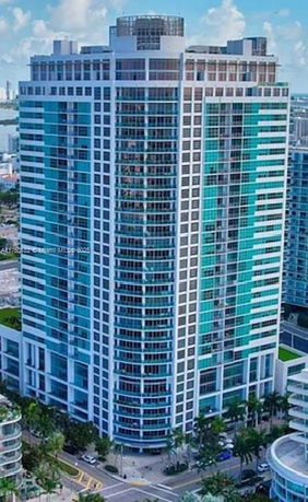 Front view of a tall modern high-rise building with blue glass windows.