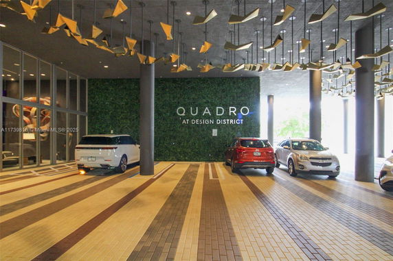 Covered parking area at Quadro Design District with parked vehicles.