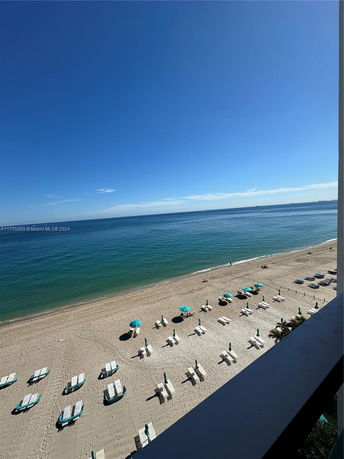 Panoramic view from a building overlooking a beach with sun loungers and umbrellas.