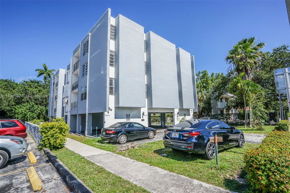 Front view of a multi-story residential building with parking area.