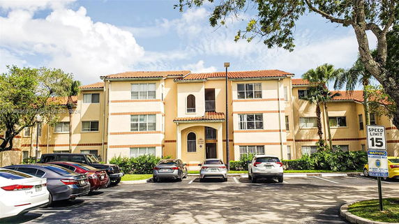 Front view of a multi-story residential building with parking area.