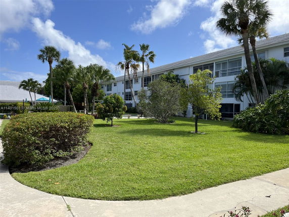 Front view of a multi-story residential building with a white facade and balconies.