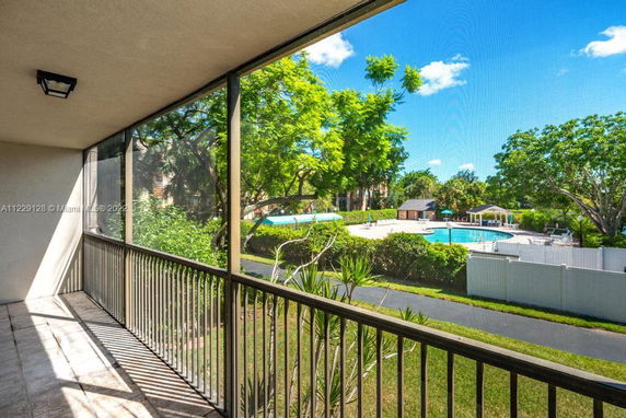View of a residential building balcony overlooking a pool and garden area.