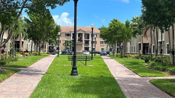 View of a residential area with a pathway leading to buildings and parked cars.