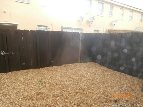 View of a fenced area with gravel ground in front of a building.