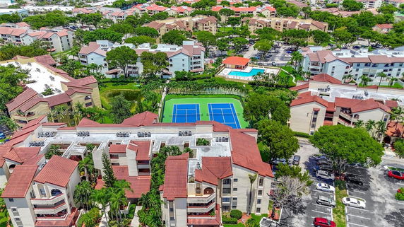 Aerial view of a residential area with multiple buildings and a tennis court.