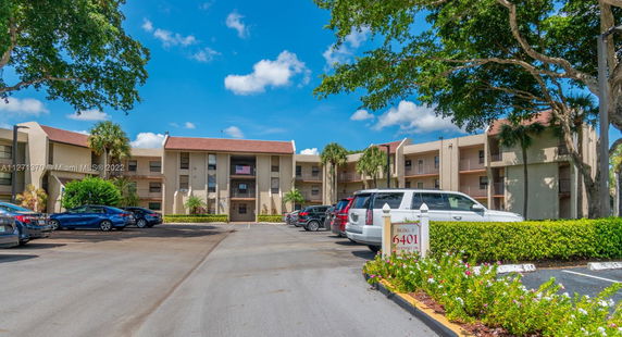 Front view of a multi-story residential building with parking area.