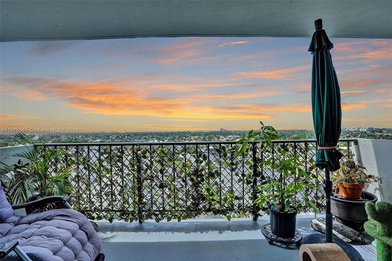 Panoramic view from a balcony showing a vast urban landscape with a scenic sunset sky.