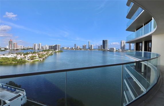 View from a balcony of a high-rise building overlooking a body of water and distant cityscape.