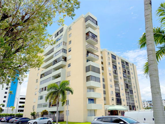 Front view of a multi-story apartment building with balconies and large windows.