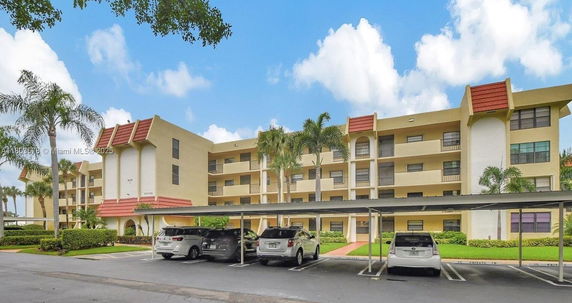 Front view of a multi-story residential building with covered parking area.