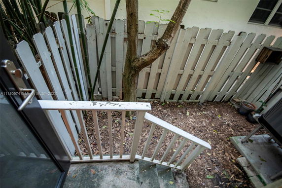 Small outdoor area with a wooden picket fence and a tree.