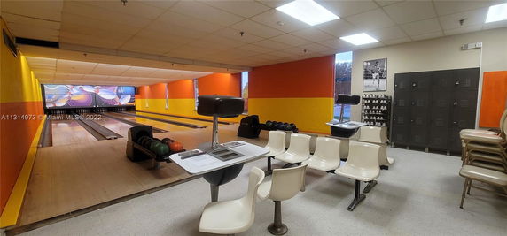 Indoor bowling alley with multiple lanes, seating area, and lockers.