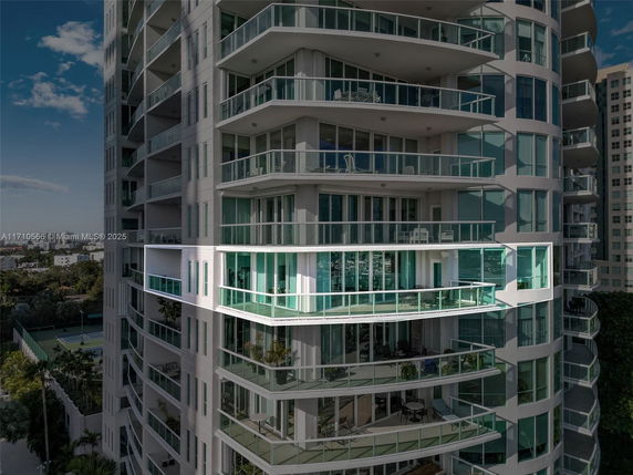 Front view of a tall building with multiple balconies and glass railings.