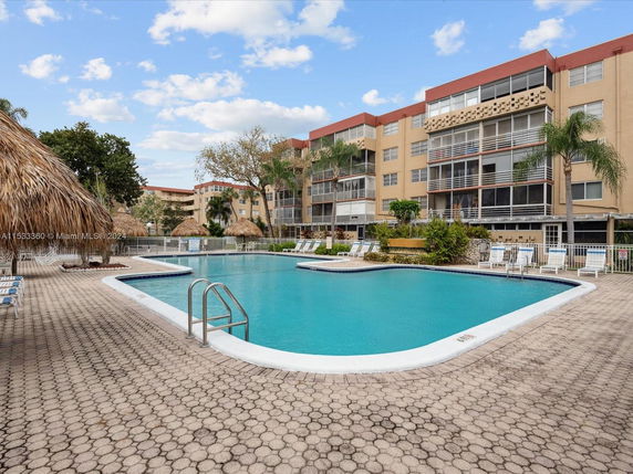 Outdoor swimming pool area with adjacent multi-story residential building.
