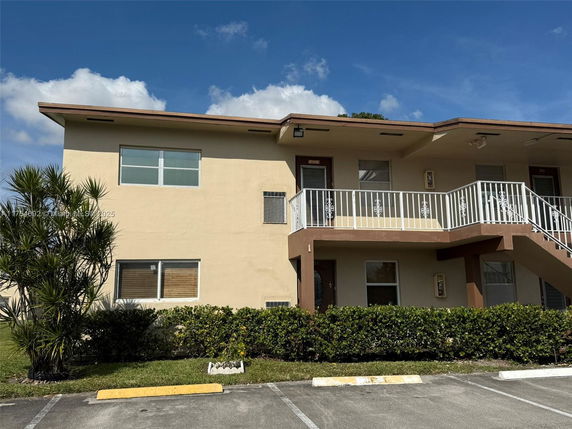 Front view of a two-story apartment building with an external staircase.