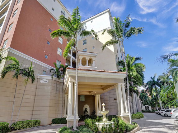 Front view of a multi-story building with a columned entrance and a fountain.