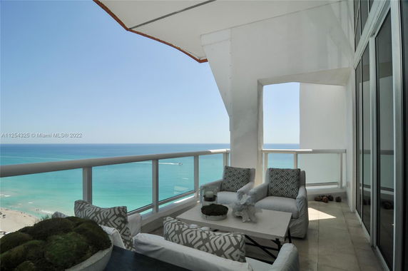Balcony view overlooking the ocean with patio furniture.