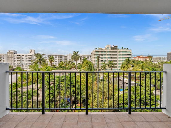 View from a balcony overlooking a group of multi-story residential buildings and lush greenery.