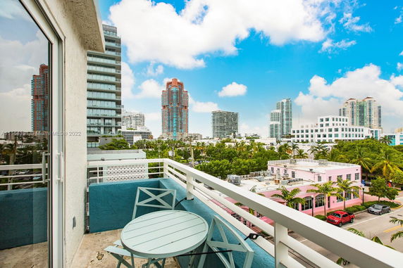 View from a balcony overlooking a cityscape with multiple high-rise buildings and a clear blue sky.