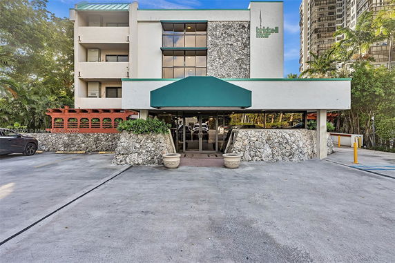 Front view of a building with stone facade and a green canopy entrance.