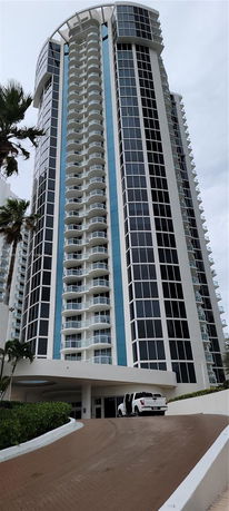 Front view of a modern high-rise building with balconies and large windows.