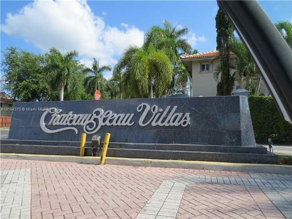 Front view of ChateauBleau Villas entrance sign with surrounding palm trees.
