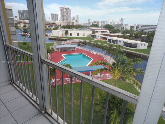 View of a swimming pool area with red flooring and surrounding buildings.