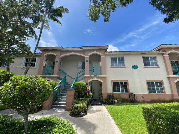 Front view of a two-story residential building with balconies and green railings.