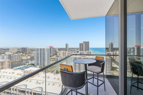 Panoramic view of a cityscape with high-rise buildings and ocean visible from a balcony.