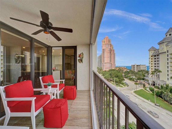 Balcony view with red cushioned seating and cityscape.