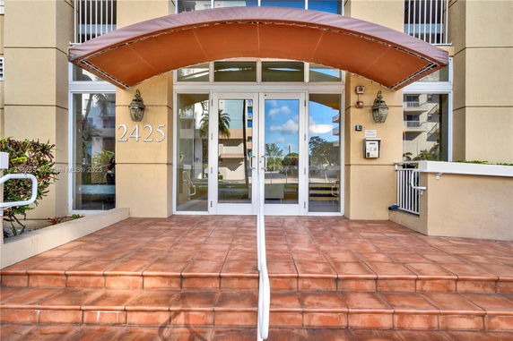 Front entrance of a building with a brown awning and glass doors.