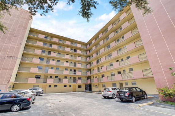 Front view of a multi-story apartment building with parking area.