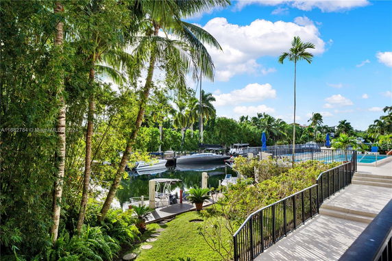 View of a waterfront area with boats docked and lush greenery surrounding.