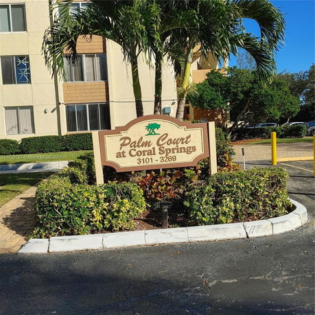 Front view of a multi-story apartment building with a sign reading 'Palm Court at Coral Springs 3101 - 3269'.
