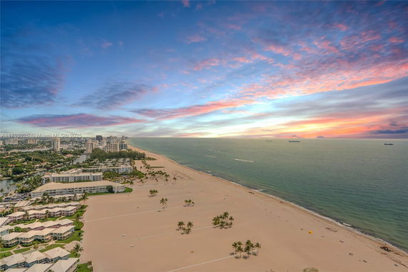 Wide angle view of a beach and ocean with buildings in the distance.