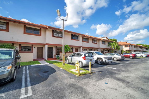 Row of townhouses with outdoor parking spaces for cars in front.