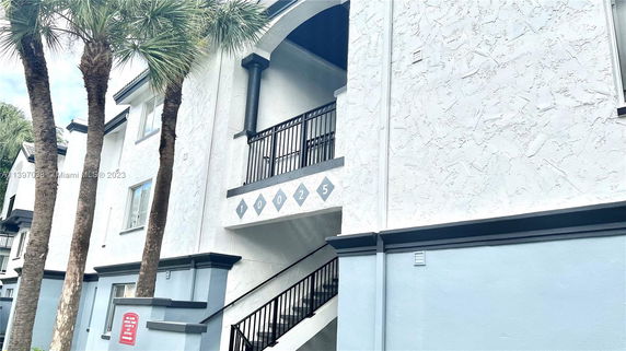 Front view of a multi-story building with stucco finish and exterior staircase.