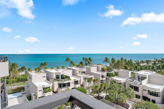 Panoramic view of modern buildings near the ocean with palm trees in the foreground.
